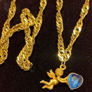 gold-tone necklace a cherub angel pendant holding a blue heart-shaped gemstone.